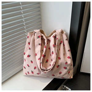 Pink corduroy tote bag with red strawberry pattern detail shown on a bright windowsill