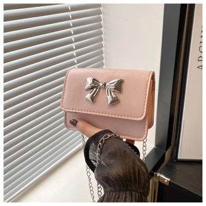 Detailed macro view of the silver metal bow buckle and leather texture on a pink bag