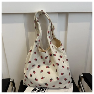Detail of soft corduroy tote bag with cute red strawberry patterns and ribbed texture