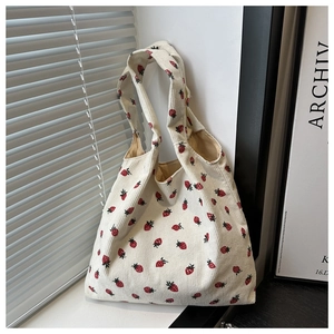 Detailed close-up of corduroy texture and red strawberry print on a creamy tote bag
