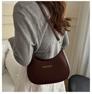 Détail du sac bandoulière demi-lune en cuir bordeaux porté avec boucles dorées