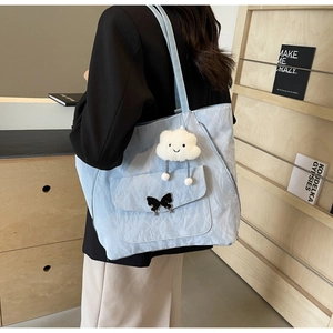 Light blue tote bag detail with butterfly pocket and cloud charm on model's shoulder