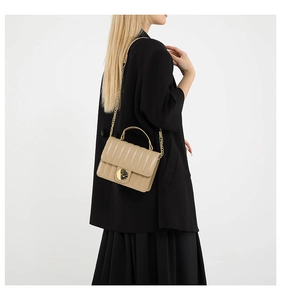 Détail d'un sac à bandoulière en cuir beige à rayures avec fermoir doré et chaîne élégante