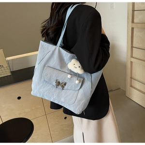 Detailed texture of light blue tote bag with silver butterfly buckle and cloud charm