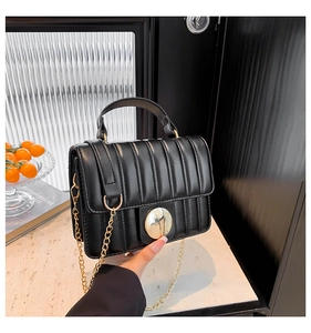 Détail du sac matelassé noir avec bandoulière chaîne dorée et boucle métallique
