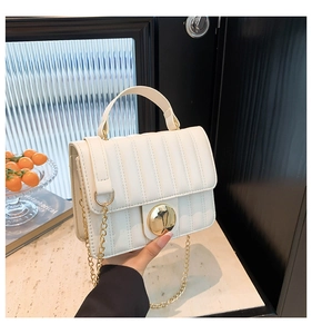 Détail du sac à bandoulière blanc matelassé avec grande boucle dorée et bandoulière chaîne