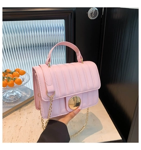 Détail d'un sac bandoulière rose matelassé avec boucle dorée et fine bandoulière chaîne