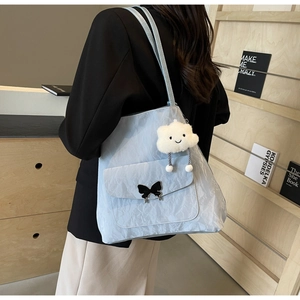 Close-up of light blue textured tote bag with metal butterfly buckle and cloud charm