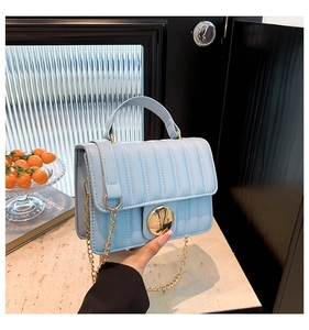 Détail du sac à main matelassé bleu clair avec fermoir doré et bandoulière chaîne