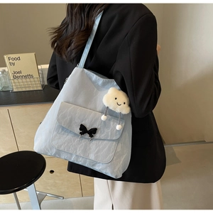 Detail of light blue pleated tote bag with metal butterfly and cloud plush charm