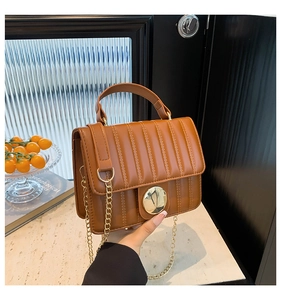 Détail du sac à main plissé marron avec boucle dorée ronde et bandoulière chaîne