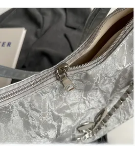 Detailed close-up of smooth silver zipper on crinkled texture silver tote bag