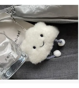 Close-up of white plush cloud charm with smiling face and striped legs on silver tote bag