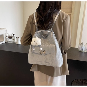Detail of silver pleated backpack with a butterfly buckle and white plush cloud charm
