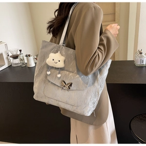 Detail of grey tote bag featuring a metallic butterfly buckle and soft cloud charm
