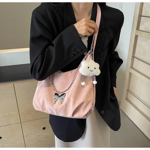 Detail of pink hobo bag with cloud charm and butterfly pendant on soft crinkled fabric