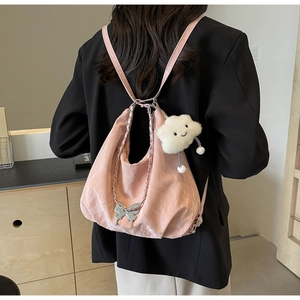 Detail of pink tote bag with silver butterfly pendant and plush cloud charm on casual strap