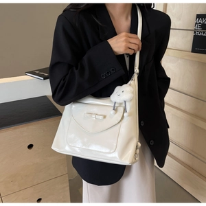 Dettaglio della borsa tote in pelle verniciata bianca con fiocco e ciondolo a nuvola