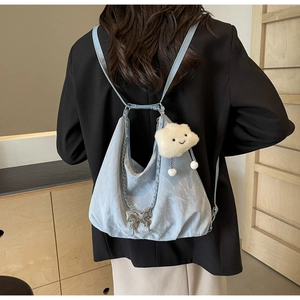 Detail of light blue pleated backpack with butterfly charm and plush cloud accessory
