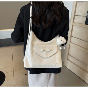 Dettaglio della borsa tote color crema con fiocco e ciondolo a nuvola di peluche