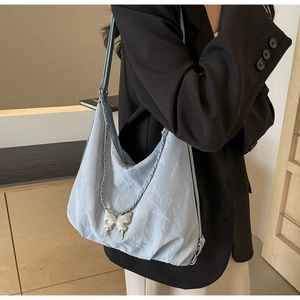 Detail of light blue hobo tote bag with silver chain and metal butterfly charm