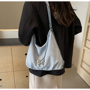 Detailed view of light blue wrinkled tote bag with silver butterfly charm and chain strap
