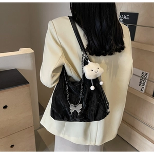 Detailed view of black wrinkled hobo bag with silver chain and cute plush charms