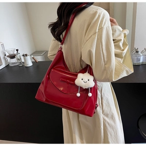 Dettaglio borsa hobo rossa lucida con fiocco e ciondolo a nuvola indossata da modella
