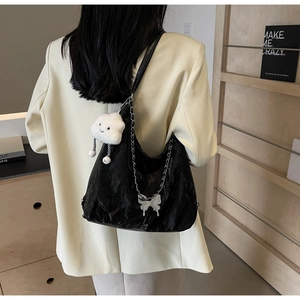 Detail of black large capacity tote bag with silver chain and plush charm on casual outfit