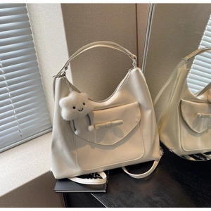 Dettaglio borsa tote in pelle color crema con tasca a fiocco e ciondolo a nuvola