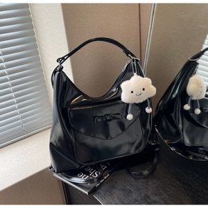 Dettaglio della borsa hobo in vernice nera con fiocco e ciondolo a nuvola di peluche