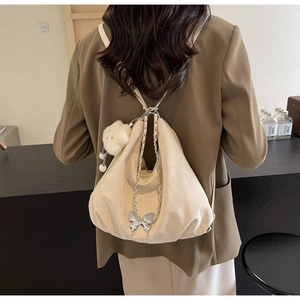 Detail of soft cream tote bag featuring metallic butterfly charm and plush cloud pendant