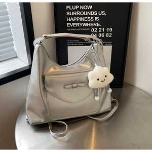 Dettaglio della borsa metallizzata argento con fiocco e ciondolo a nuvola sul tavolo