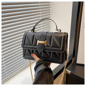 Close-up of black triangle-quilted leather handbag with a gold rectangular metal clasp