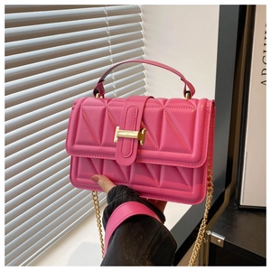 Detail of pink quilted crossbody bag with gold chain strap and metallic buckle closure