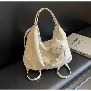 Detail of cream hobo tote featuring silver butterfly charm and soft cloud plush pendant