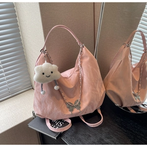 Detailed shot of pink hobo bag with butterfly charm, plush cloud pendant and metal chain