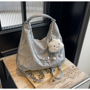 Close-up of silver tote bag with crinkled texture, metal butterfly and plush cloud charm