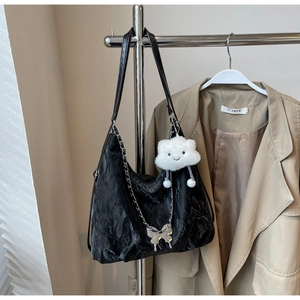 Detail of black pleated tote bag with silver butterfly chain and plush charm