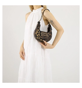 Detalle de bolso medialuna con estampado de leopardo y hebilla dorada sobre vestido blanco