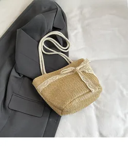Detail of woven straw tote bag featuring white lace bow and thick cotton rope handles