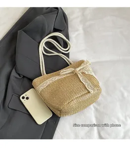 Detail view of woven straw tote bag with lace bow and cotton rope handle showing size scale
