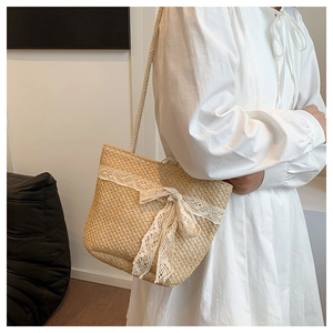 Detail of summer straw bag with white lace trim and large bow decoration on the side