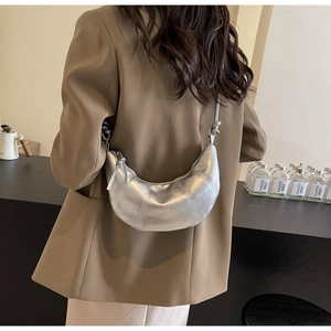 Silver hobo bag with metallic finish and knot detail worn by a model in casual setting