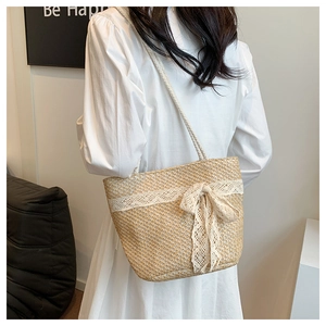 Detail of woven straw tote bag featuring delicate white lace trim and bow accent