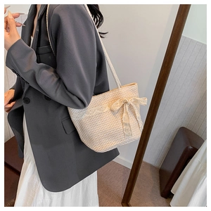 Detail showing natural straw weave texture and elegant lace bow on white tote bag