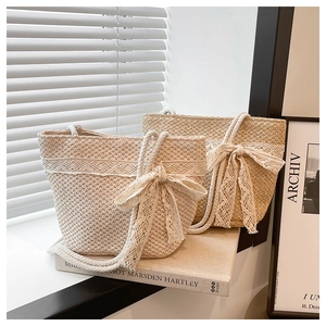 Detailed shot of two woven straw bucket bags with white lace trim and bow decorations