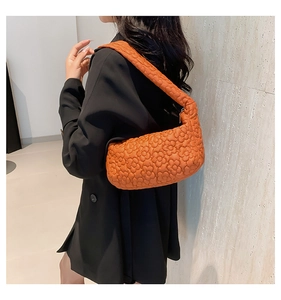 Detail van oranje gewatteerde halvemaanvormige tas met wolktextuur op model