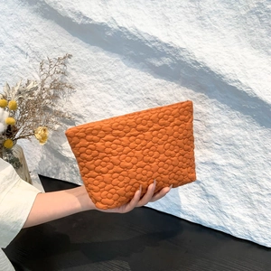 Gevoerde make-up tas in fel oranje met geborduurde bloemen en zachte structuur