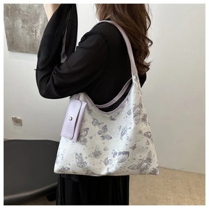 White tote bag with purple butterfly print and small matching coin purse on model